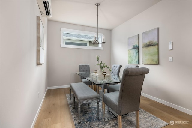 dining room with a chandelier, a wall mounted air conditioner, wood finished floors, and baseboards