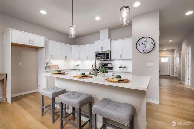 kitchen with white cabinetry, appliances with stainless steel finishes, light countertops, and backsplash