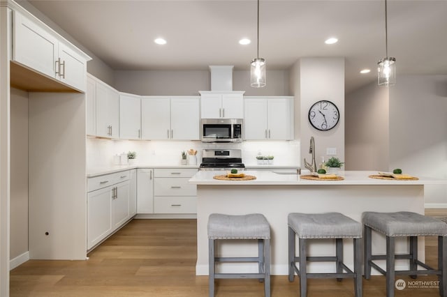 kitchen with light countertops, appliances with stainless steel finishes, a kitchen bar, and white cabinetry