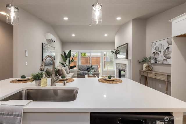 kitchen featuring light countertops, a wall mounted AC, a glass covered fireplace, open floor plan, and a sink