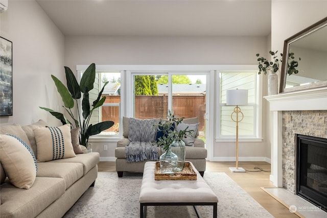 living room with wood finished floors, a fireplace with flush hearth, and baseboards