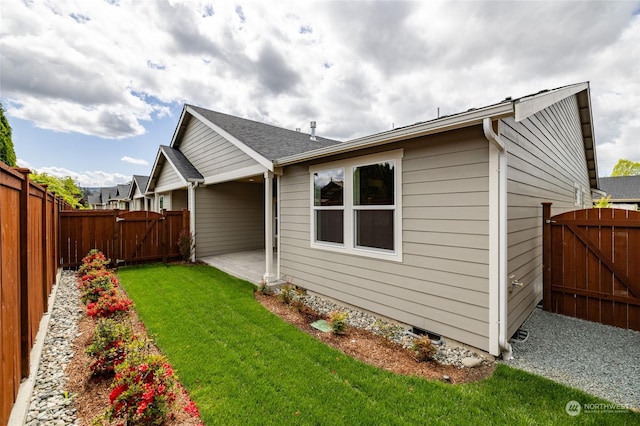 back of property with a gate, a fenced backyard, a yard, and a patio