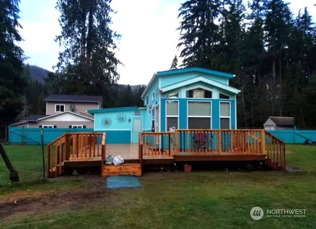 rear view of property featuring a lawn and a deck