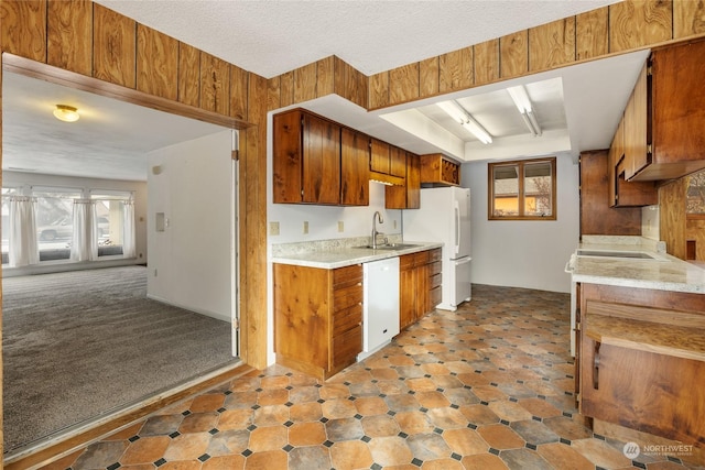 kitchen featuring a textured ceiling, white appliances, wooden walls, and sink