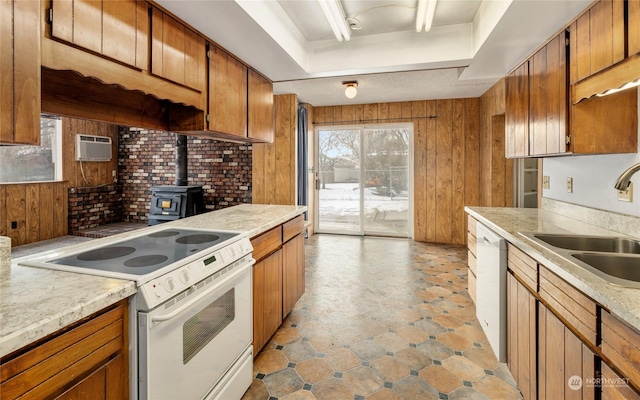 kitchen featuring wood walls, white appliances, a wood stove, sink, and a wall mounted AC