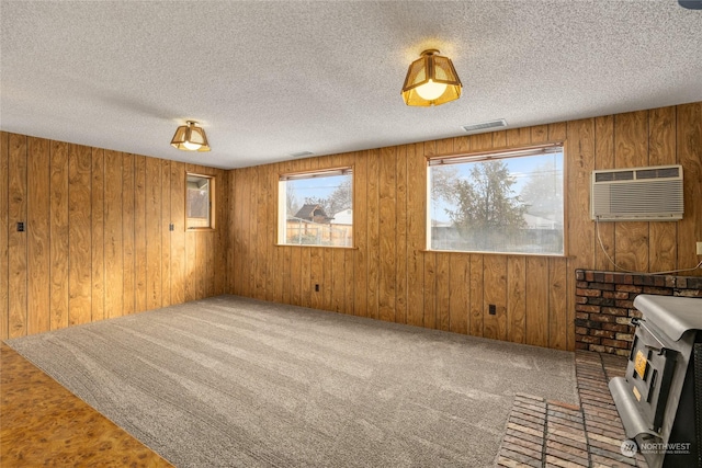 unfurnished living room with a wall mounted air conditioner, wood walls, and a textured ceiling