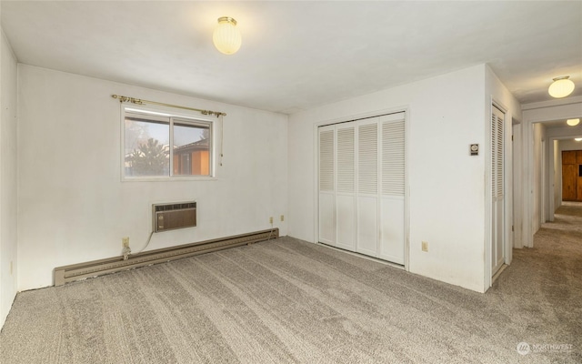 unfurnished bedroom featuring a wall mounted air conditioner, carpet, and a baseboard radiator