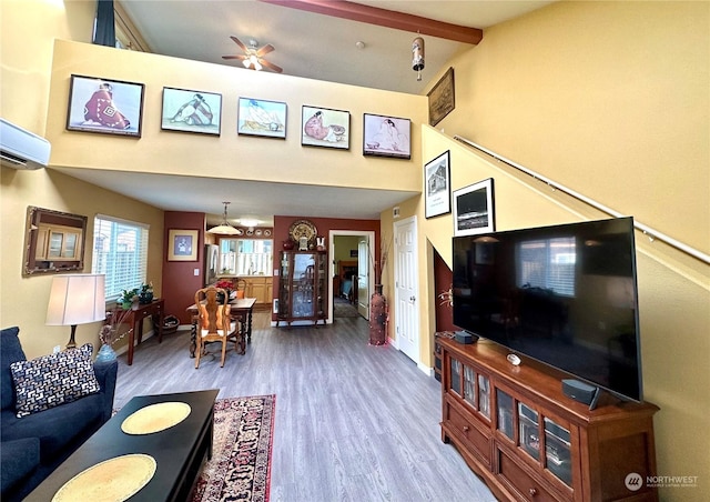 living room featuring hardwood / wood-style floors, ceiling fan, vaulted ceiling with beams, and an AC wall unit