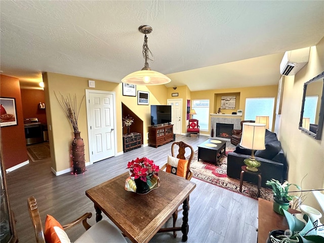 dining area featuring hardwood / wood-style floors, a fireplace, a wall unit AC, and a textured ceiling