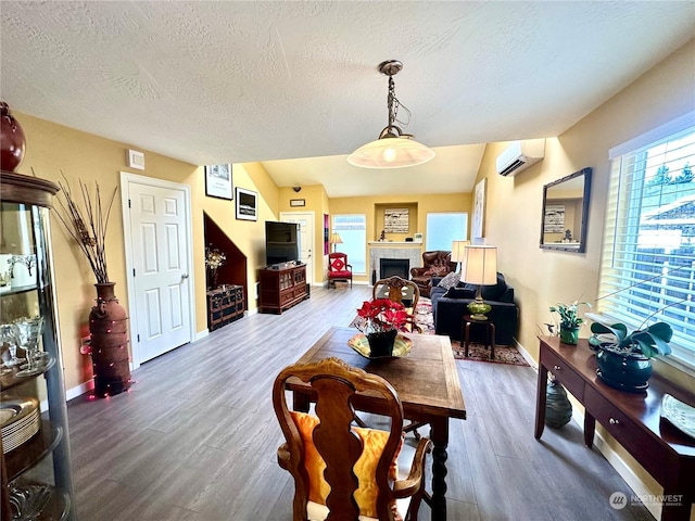 dining room featuring hardwood / wood-style floors, a textured ceiling, a fireplace, and a wall mounted AC