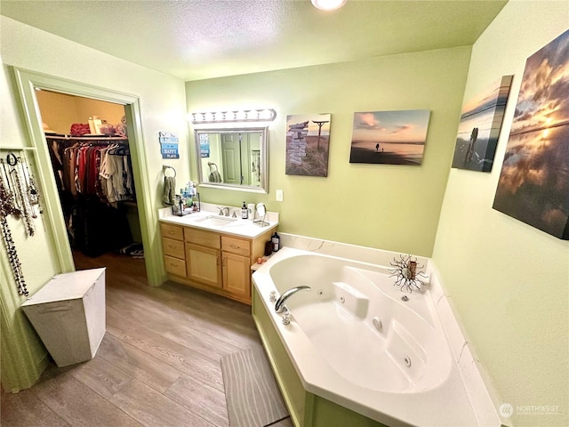 bathroom featuring vanity, a textured ceiling, hardwood / wood-style flooring, and a tub