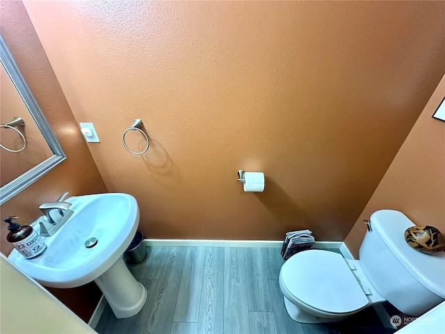 bathroom with wood-type flooring, toilet, and sink