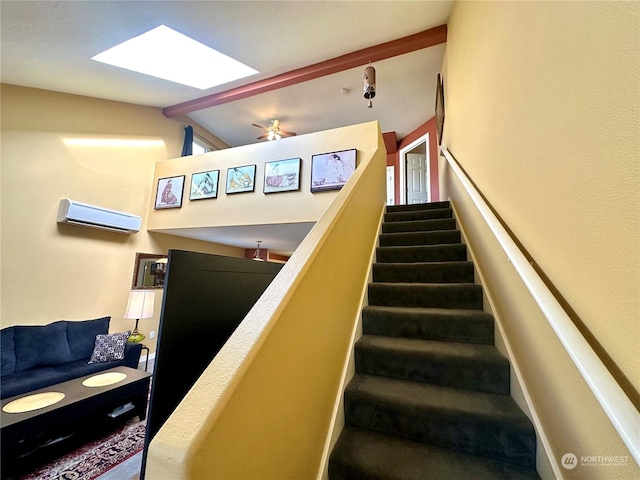 staircase with an AC wall unit and vaulted ceiling with skylight