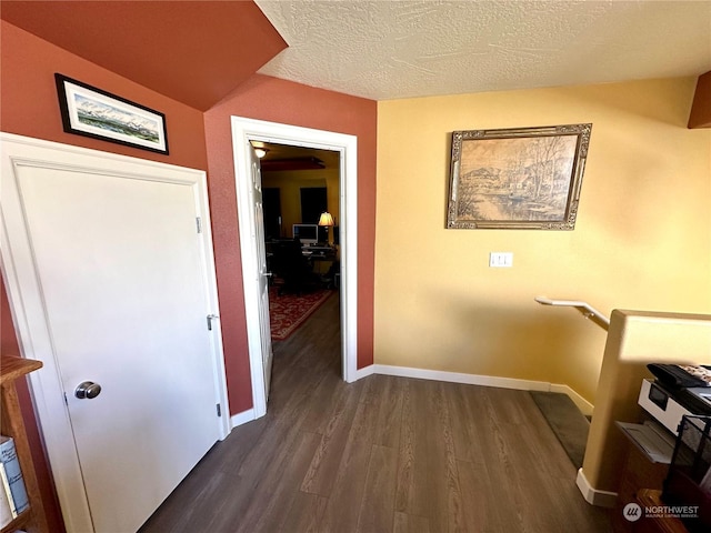 corridor with a textured ceiling and dark hardwood / wood-style floors