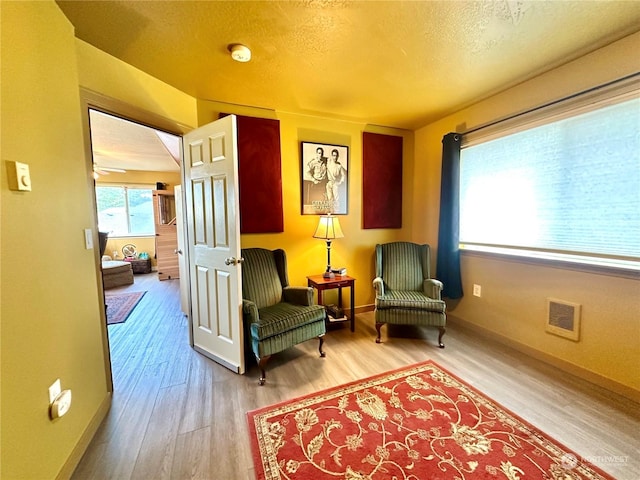 living area featuring ceiling fan, wood-type flooring, and a textured ceiling