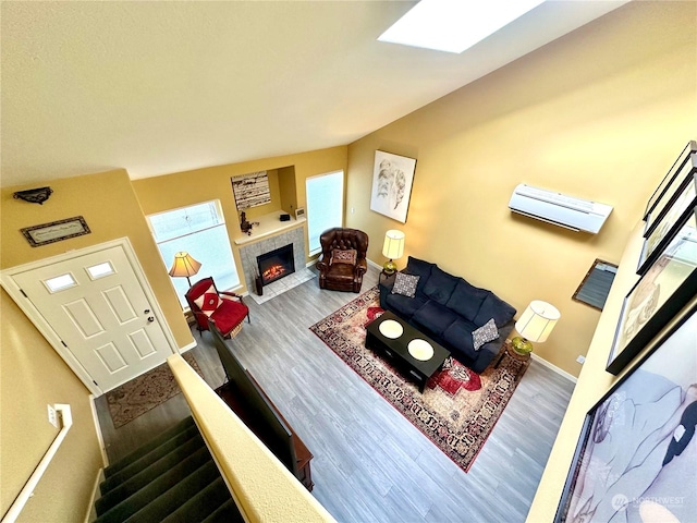 living room with hardwood / wood-style flooring, a skylight, and a tiled fireplace