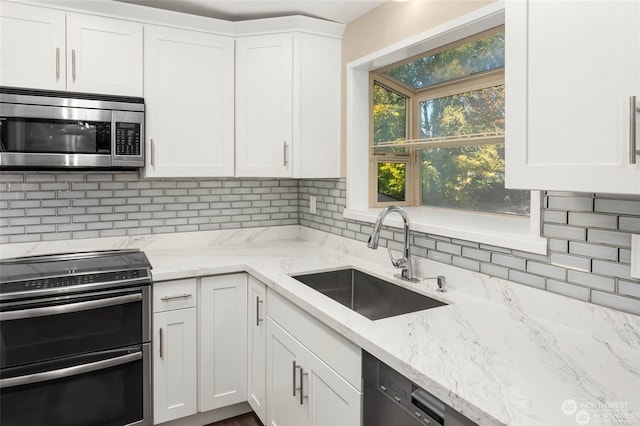 kitchen with white cabinetry, sink, decorative backsplash, and stainless steel appliances