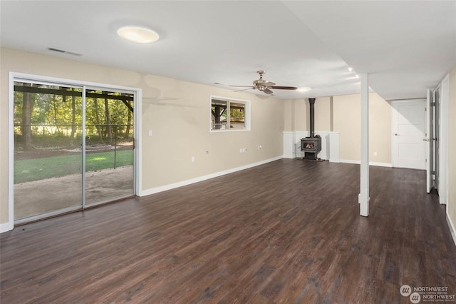 unfurnished living room with dark hardwood / wood-style floors, ceiling fan, and a wood stove