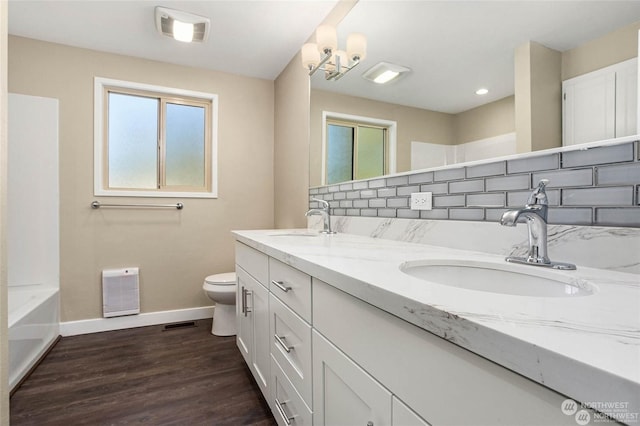 bathroom featuring wood-type flooring, toilet, vanity, and backsplash