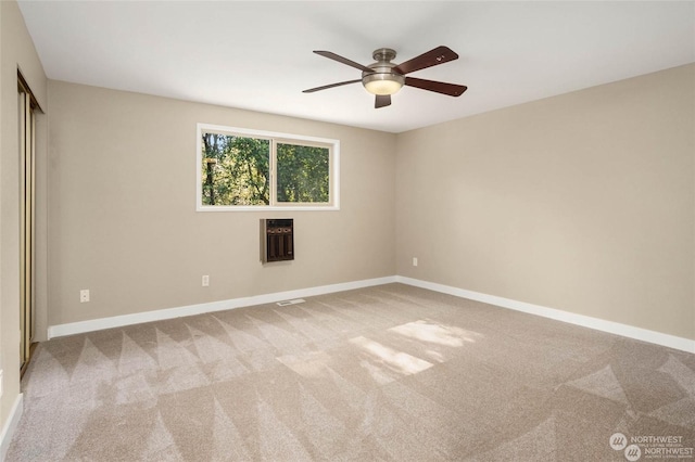 carpeted empty room featuring ceiling fan and heating unit