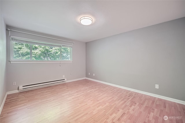 spare room with baseboard heating and light hardwood / wood-style flooring