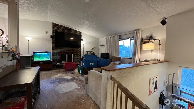 living room with a textured ceiling, vaulted ceiling, and a brick fireplace