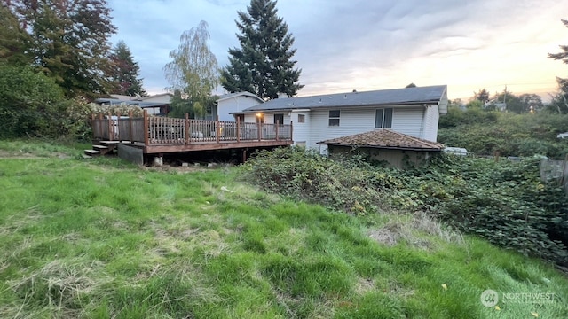 back house at dusk featuring a wooden deck