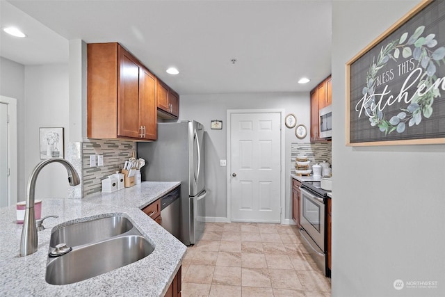 kitchen with decorative backsplash, appliances with stainless steel finishes, light stone countertops, sink, and light tile patterned flooring