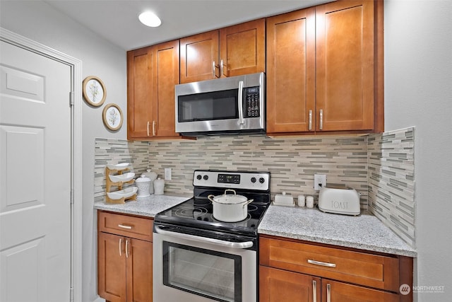 kitchen with light stone counters, backsplash, and appliances with stainless steel finishes