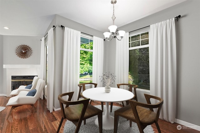 dining room featuring a tile fireplace, a chandelier, and dark hardwood / wood-style floors