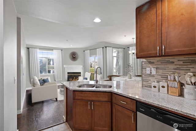 kitchen featuring kitchen peninsula, light stone countertops, sink, dishwasher, and a tiled fireplace