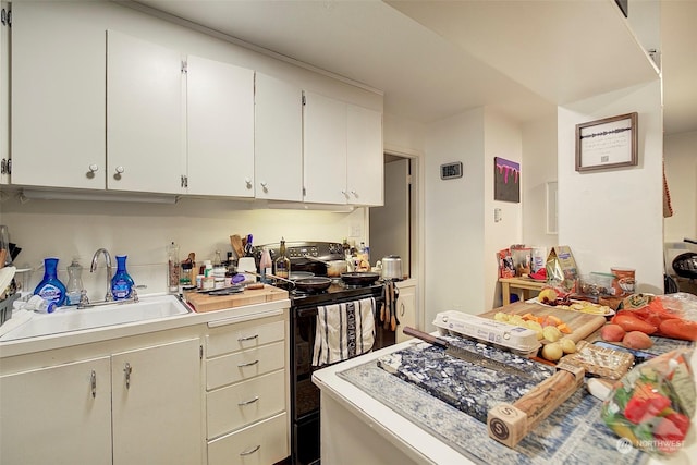 kitchen with black range with electric stovetop, sink, and white cabinets