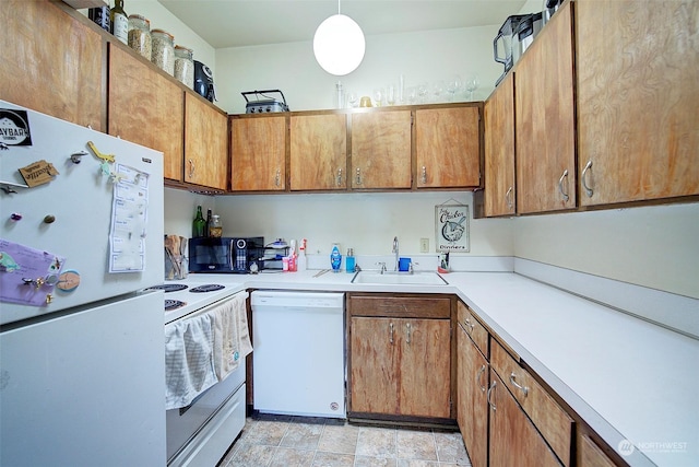 kitchen featuring white appliances, hanging light fixtures, and sink