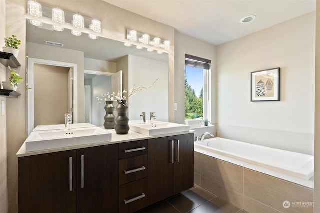 bathroom featuring tile patterned flooring, vanity, and tiled tub