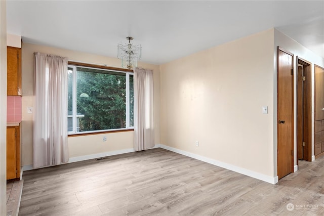 unfurnished dining area featuring light hardwood / wood-style flooring and an inviting chandelier