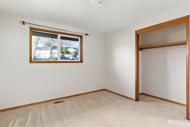 unfurnished bedroom featuring light colored carpet and a closet