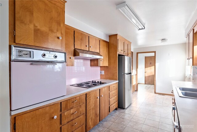 kitchen featuring white appliances, sink, light tile patterned floors, and tasteful backsplash