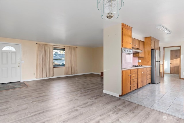 kitchen featuring white oven, stainless steel refrigerator, light hardwood / wood-style floors, and gas stovetop