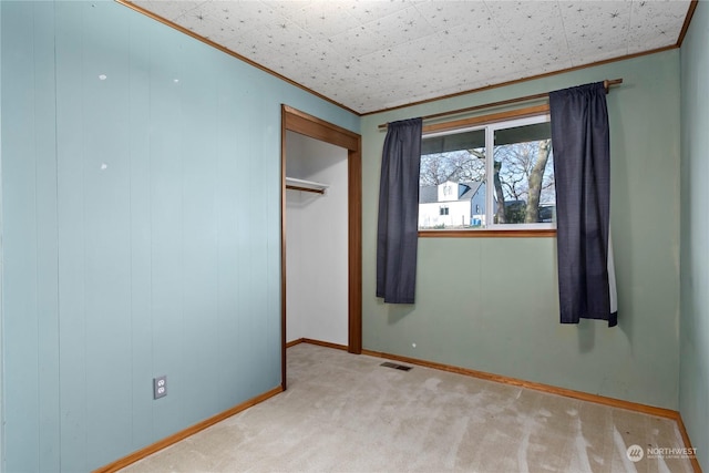 unfurnished bedroom with a closet, light colored carpet, and ornamental molding