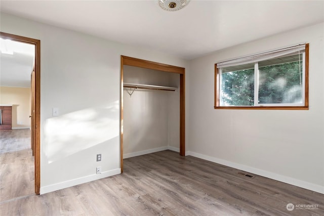 unfurnished bedroom with light wood-type flooring and a closet