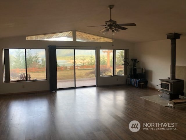 unfurnished living room featuring ceiling fan, a wood stove, dark wood-type flooring, and vaulted ceiling