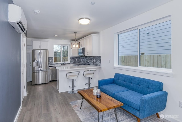 living room featuring a wall mounted air conditioner, sink, and hardwood / wood-style floors