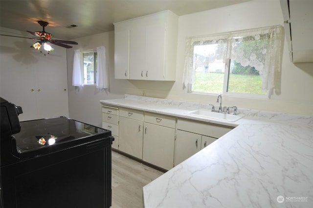 kitchen with light wood-type flooring, ceiling fan, sink, black electric range, and white cabinetry