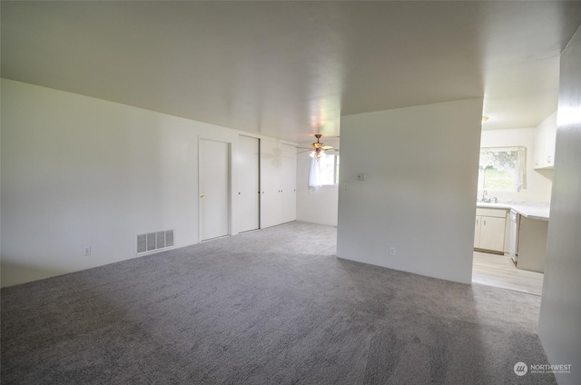 empty room with ceiling fan, light colored carpet, and a wealth of natural light