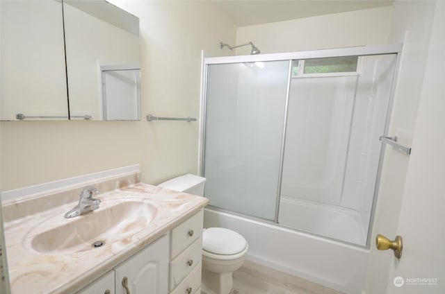 full bathroom with combined bath / shower with glass door, vanity, and toilet