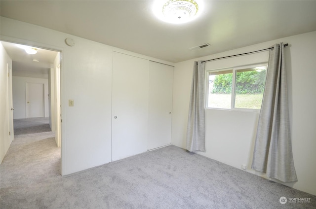 unfurnished bedroom featuring light carpet and a closet