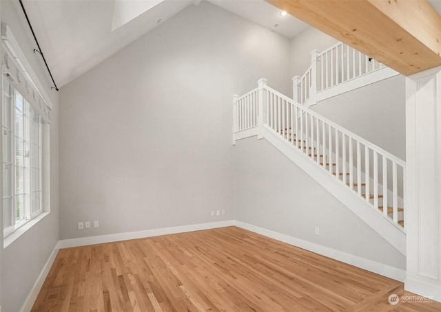 stairway with high vaulted ceiling, wood-type flooring, and plenty of natural light