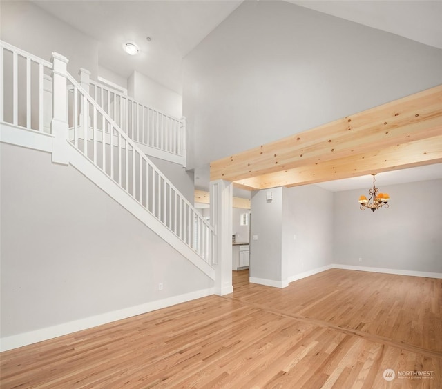 unfurnished living room with a high ceiling, a chandelier, and hardwood / wood-style floors