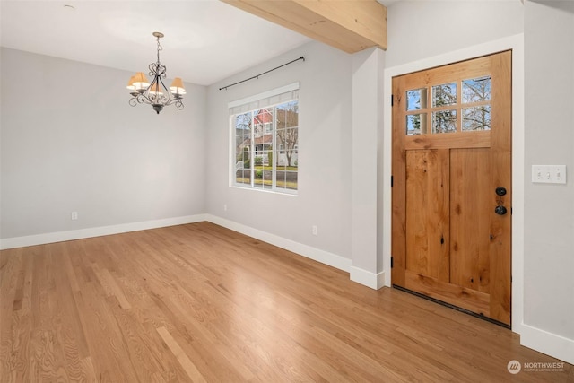 foyer entrance with beamed ceiling, light hardwood / wood-style floors, and a chandelier