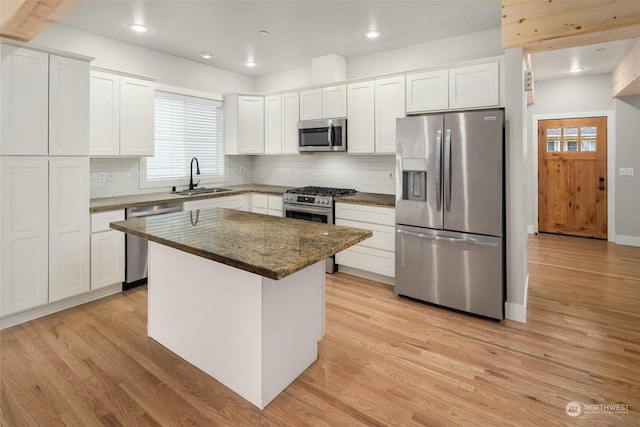 kitchen with appliances with stainless steel finishes, a center island, white cabinets, and dark stone countertops